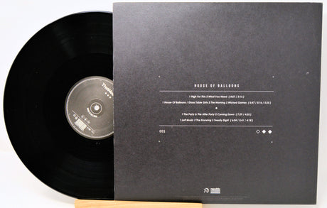 Vinyl record with its cover displaying tracklist on a white background