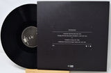 Black vinyl record with a matching black sleeve on a white background