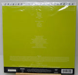 The back cover of a vinyl record sleeve, featuring a bright lime green background with white text listing track titles and credits, sealed in its plastic shrink wrap.
