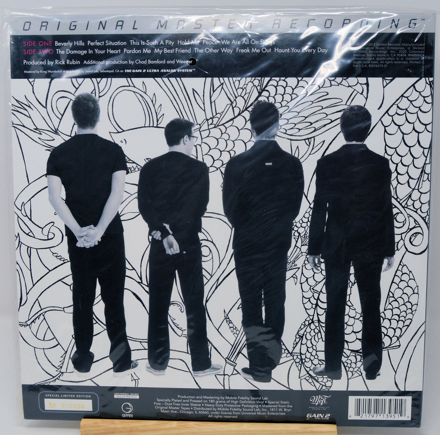 The back cover of the vinyl record 'Original Mystery Reptile' by the band EAGLE, featuring a black and white illustration of four men in suits from behind against a patterned background.