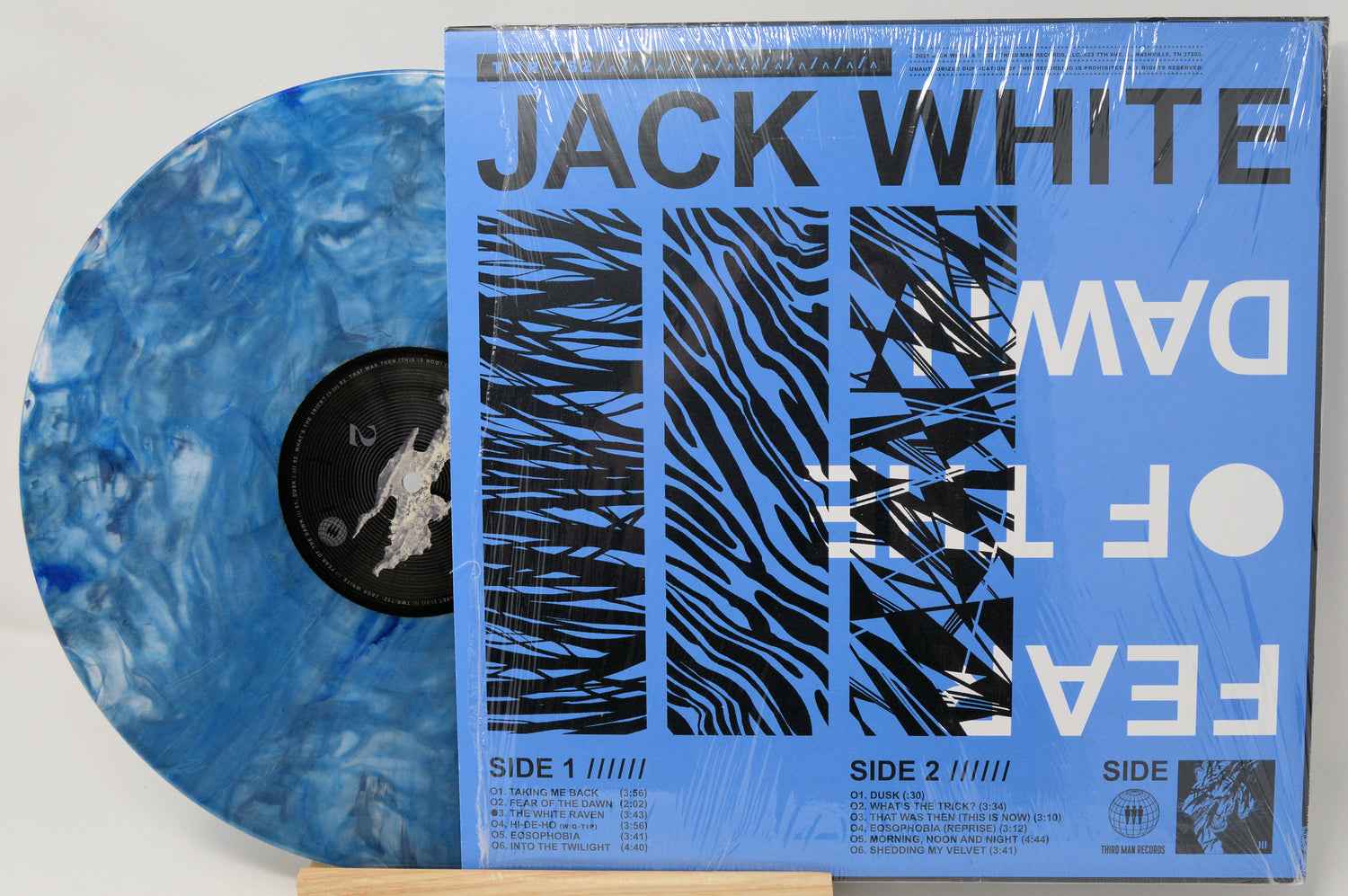 Vinyl record with blue marbled design and a patterned cover featuring 'Jack White' and 'Dawes'.