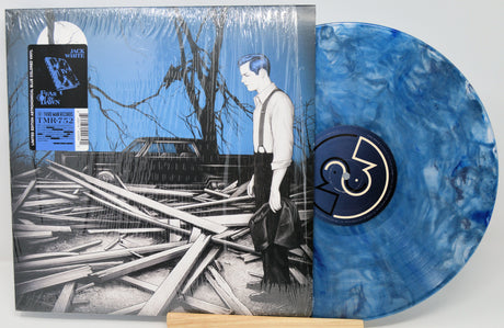 Vinyl record with blue marbled design and cover featuring a person and destroyed building.