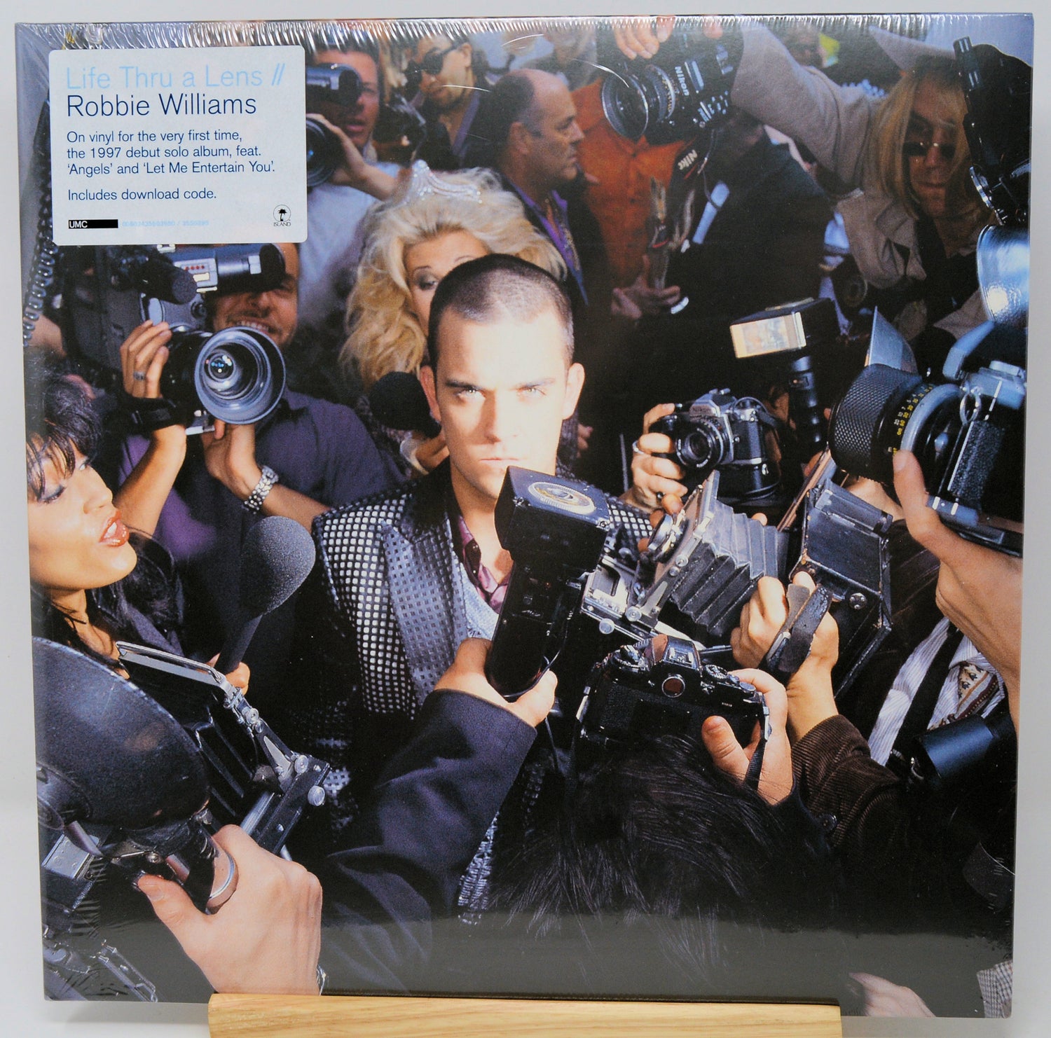 Vinyl record cover with a collage of a man surrounded by photographers and cameras.