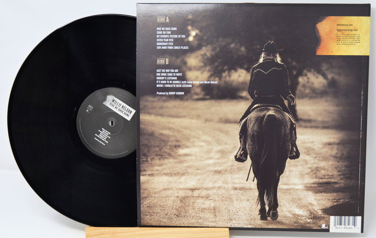 A vinyl record partially pulled from its album jacket, showing the black record on the left and the back cover artwork on the right. The cover features a sepia-toned photo of a rider on a horse from behind, with track listing text and a small orange label area in the top right.