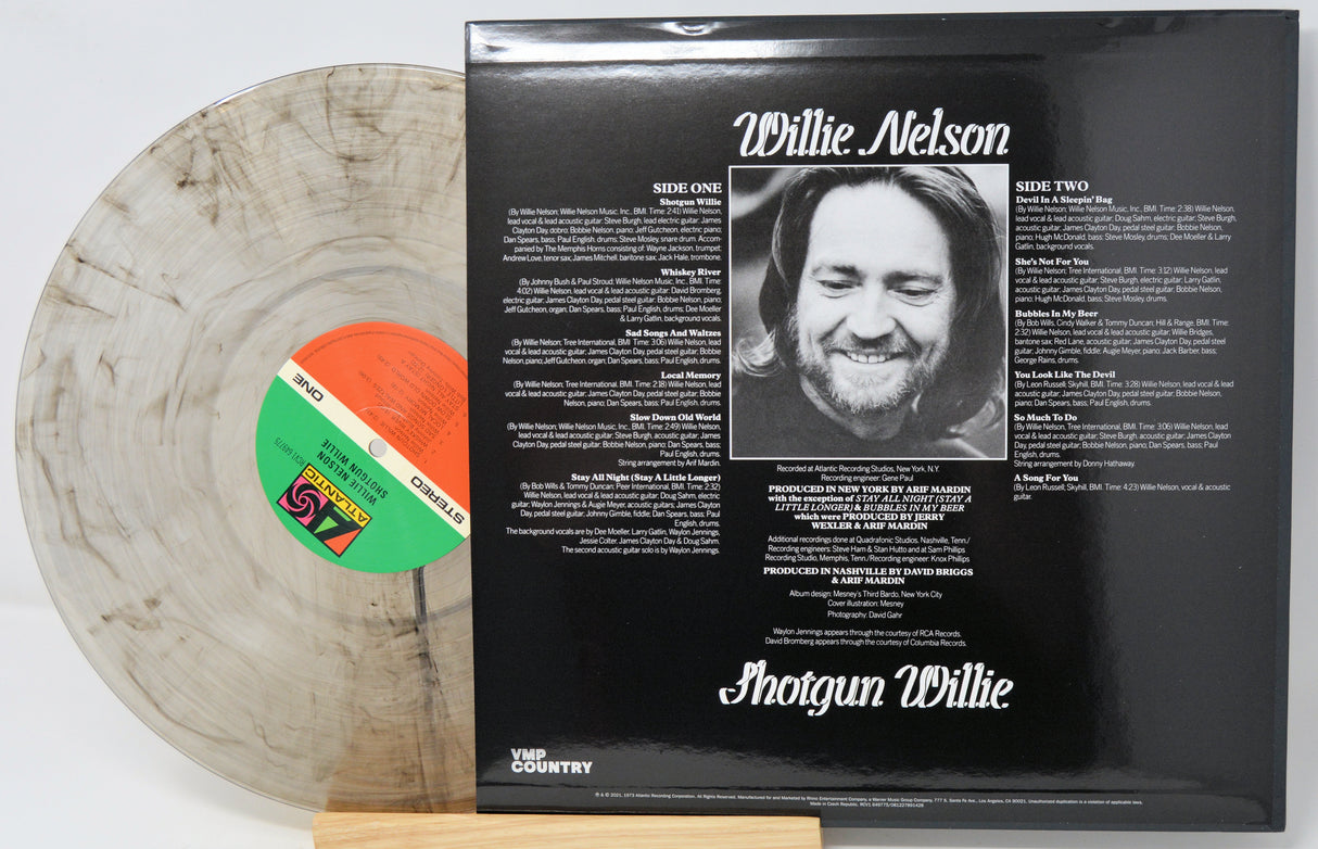 Willie Nelson 'Shotgun Willie' vinyl record LP shown with the back cover standing upright and the record partially pulled out. The record is translucent smoky gray with a green and orange label, and the back cover is black with white text and a black-and-white portrait.