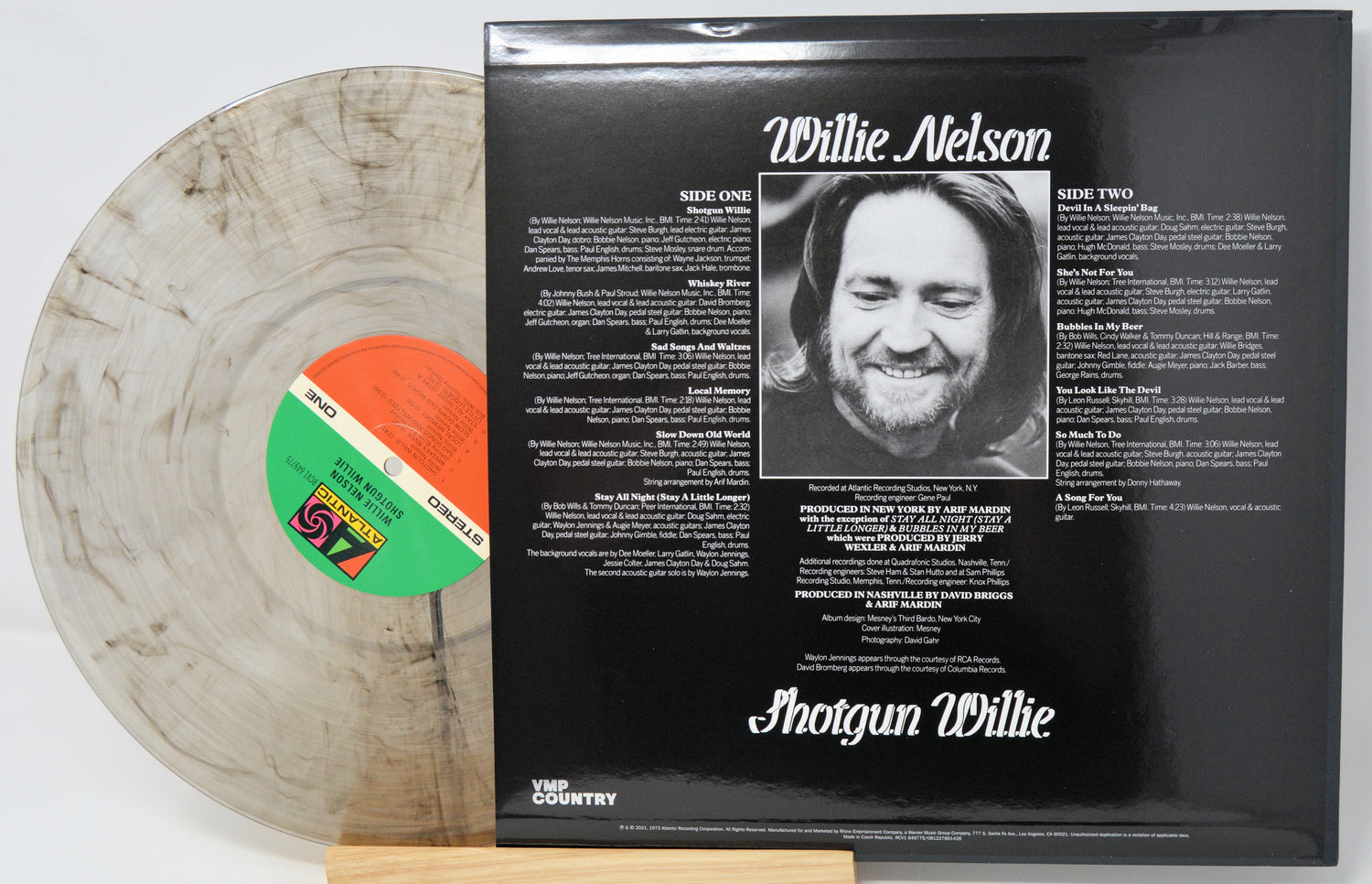 Willie Nelson 'Shotgun Willie' vinyl record LP shown with the back cover standing upright and the record partially pulled out. The record is translucent smoky gray with a green and orange label, and the back cover is black with white text and a black-and-white portrait.