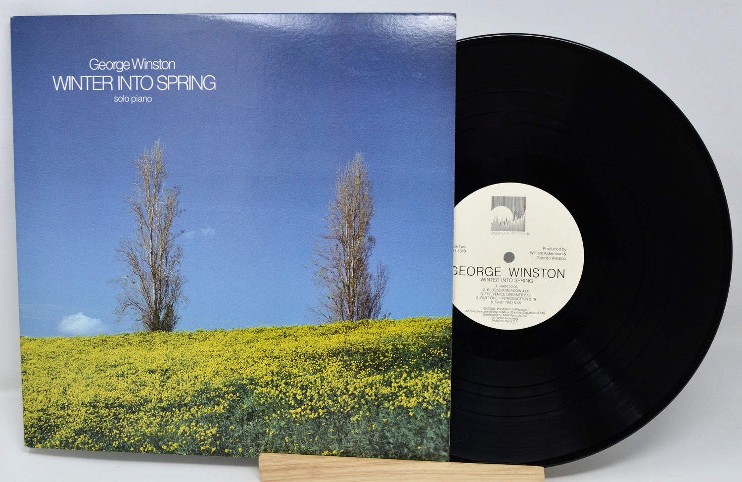 Vinyl record with cover featuring a landscape of trees and flowers, labeled 'Winter into Spring' by George Winston.