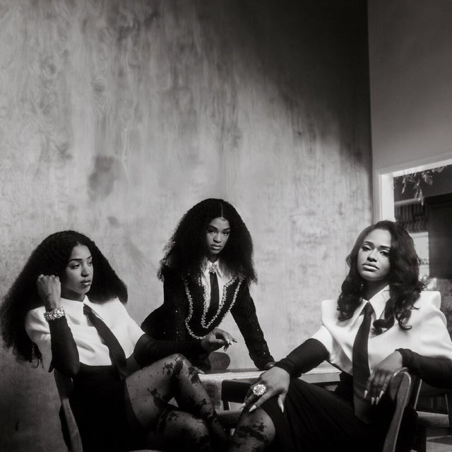 Black and white photo of three women sitting together in a room with a textured wall.