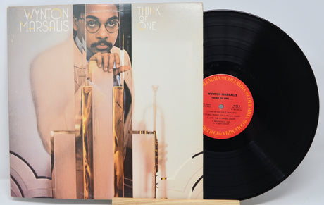 Vinyl record with cover featuring a person, on a light gray background