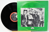 Vinyl record with green cover featuring a black and white photo of four people, on a light gray background.