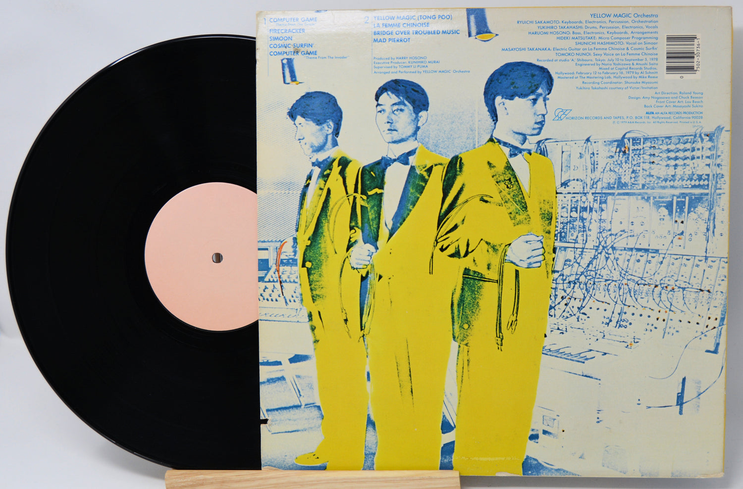 Vinyl record with a cover featuring three people in yellow suits on a white background