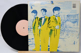 Vinyl record with a cover featuring three people in yellow suits on a white background
