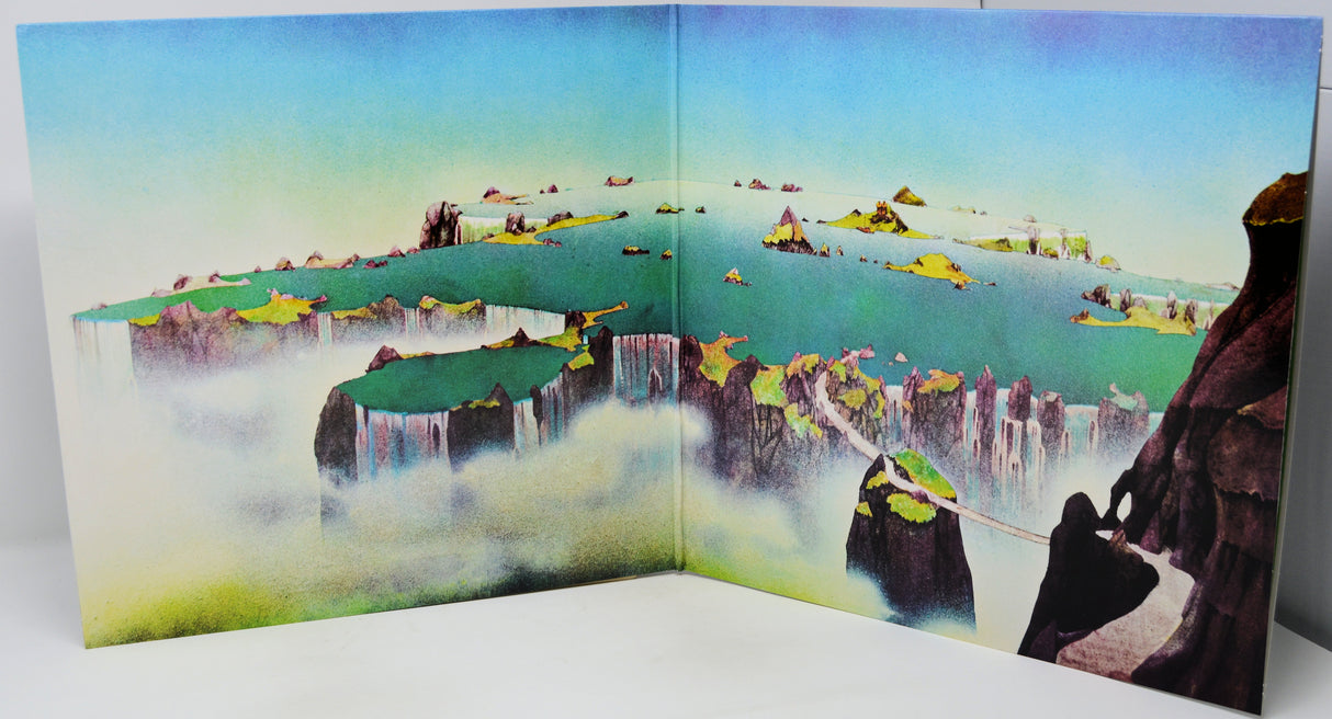 A three-dimensional paper diorama model depicting a fantasy landscape with floating islands, waterfalls, and a figure climbing a cliff, shown against a plain white background.