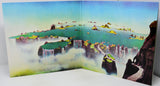 A three-dimensional paper diorama model depicting a fantasy landscape with floating islands, waterfalls, and a figure climbing a cliff, shown against a plain white background.