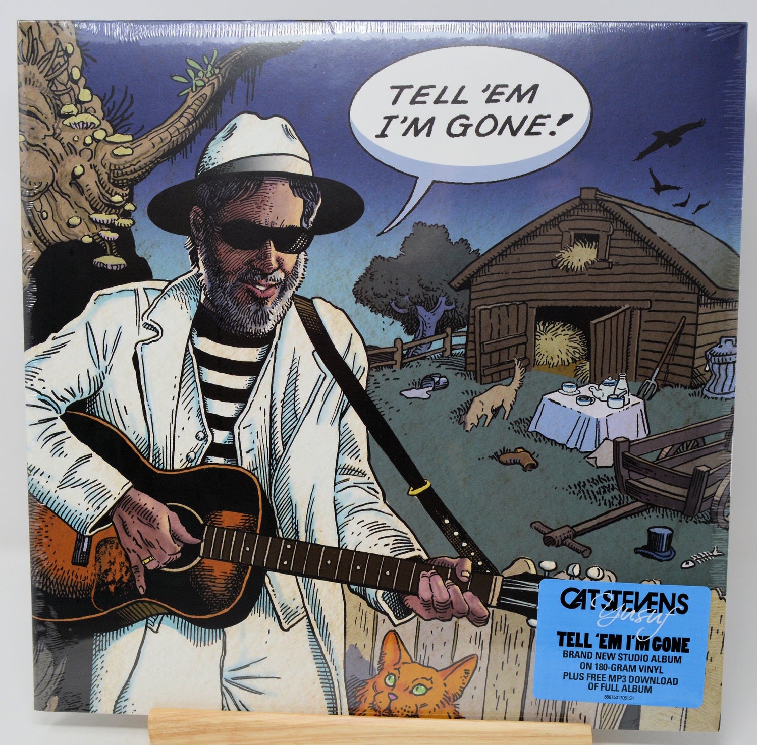 Cat Stevens 'Tell 'Em I'm Gone' vinyl record album cover, showing an illustrated man in a white suit and hat playing an acoustic guitar, with a blue sticker label in the lower right corner.