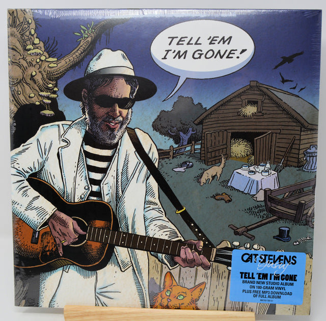Cat Stevens 'Tell 'Em I'm Gone' vinyl record album cover, showing an illustrated man in a white suit and hat playing an acoustic guitar, with a blue sticker label in the lower right corner.