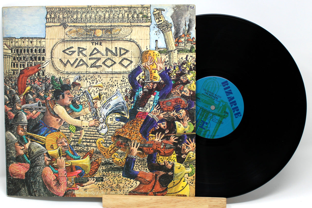 A vinyl record of Frank Zappa's album 'Grand Wazoo' with a colorful, artistic cover featuring a crowd and musical instruments.