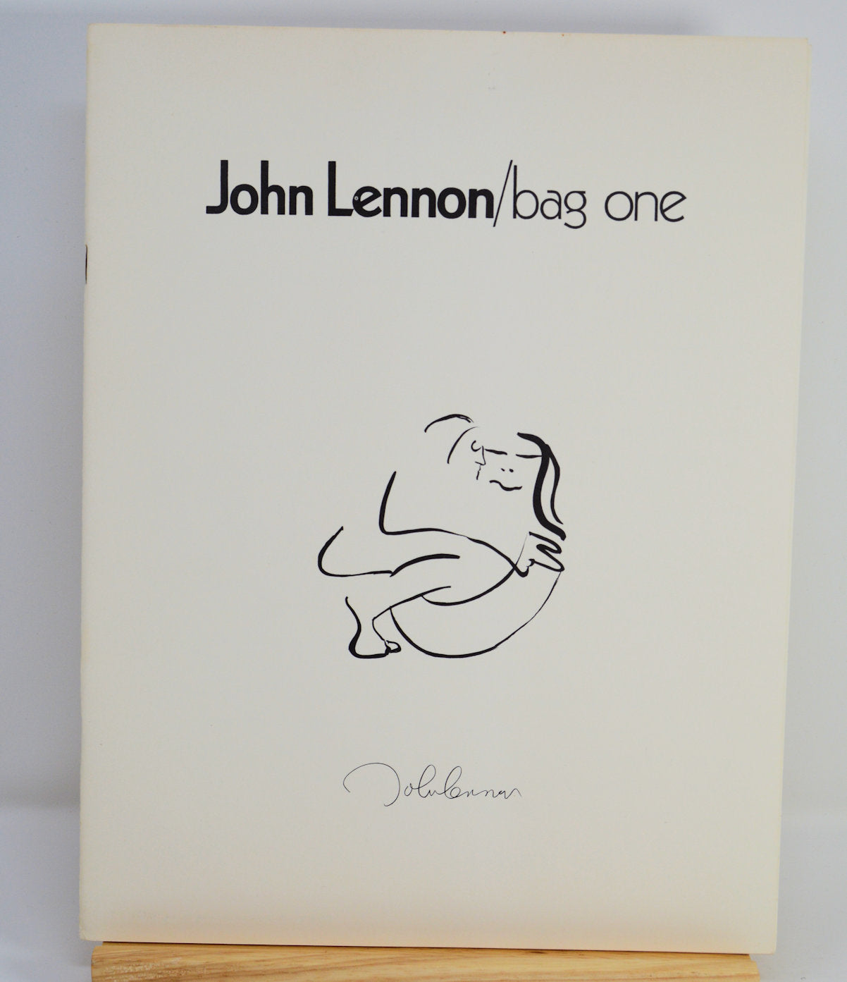 Book titled 'John Lennon/bag one' with a minimalistic design on a white background
