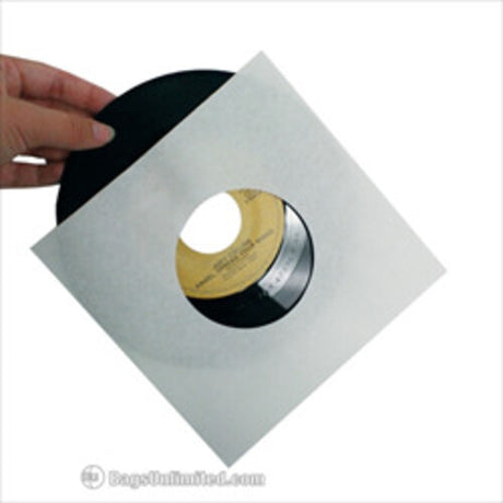 A hand holding a silver-colored 45 sleeve with a vinyl record inside, against a white background.