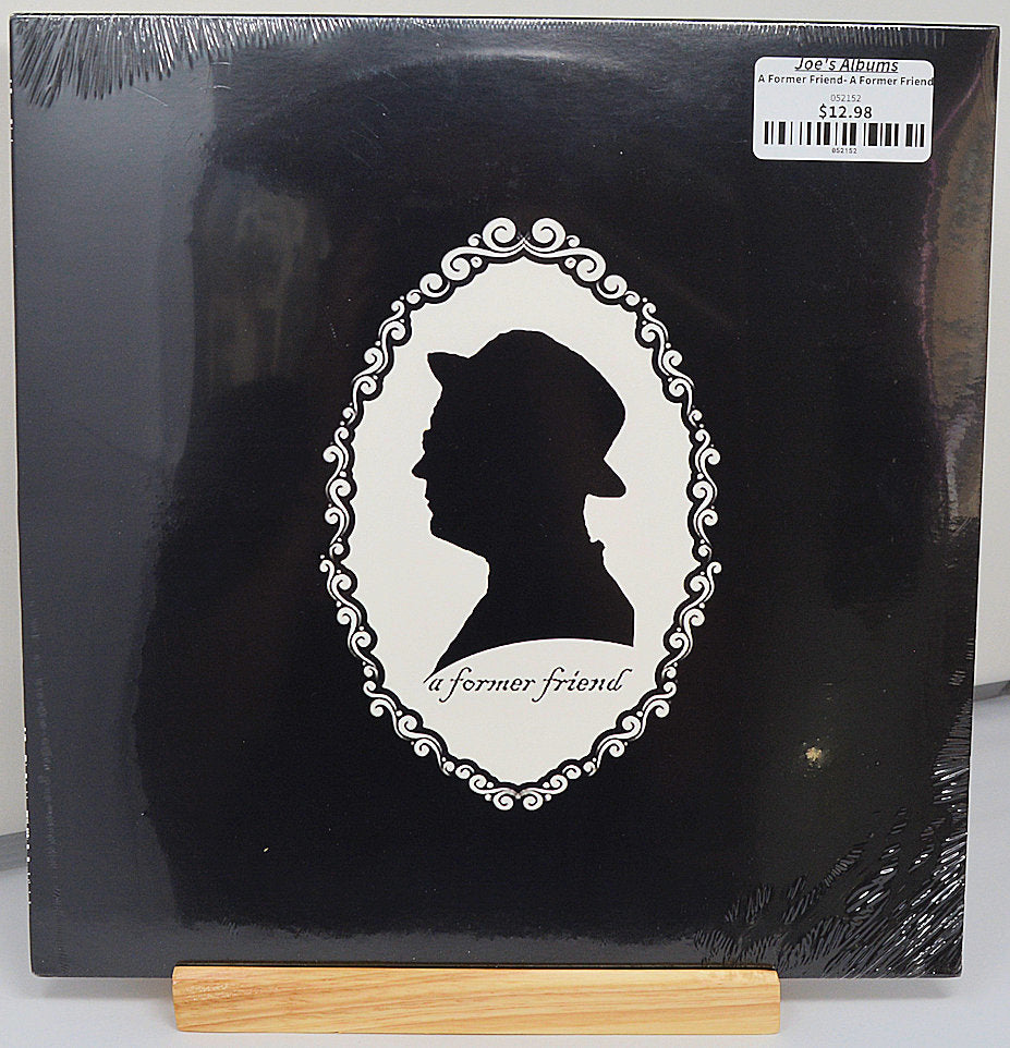 A black vinyl record labeled 'A Former Friend' by The Cranberries with a white-outlined portrait of a man's head and the band's name on the cover.