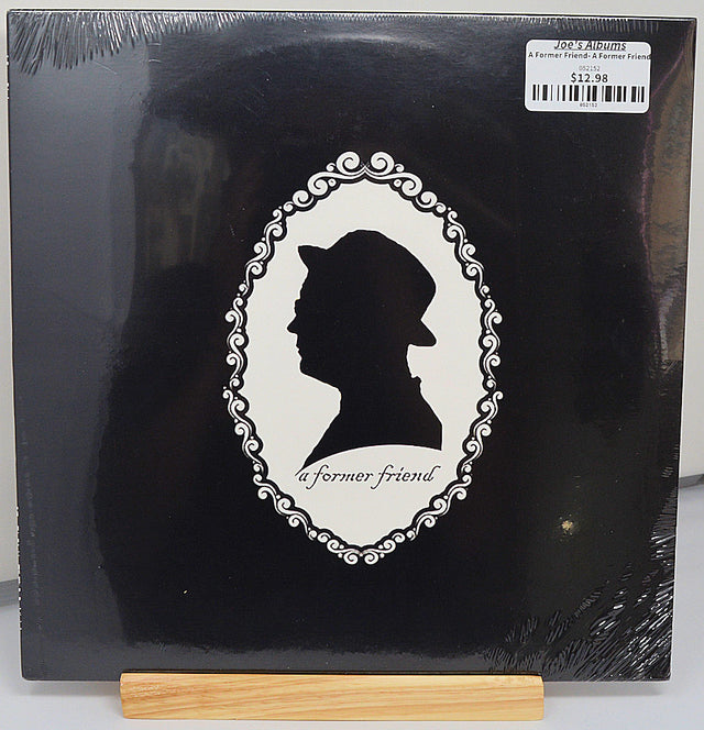 A black vinyl record labeled 'A Former Friend' by The Cranberries with a white-outlined portrait of a man's head and the band's name on the cover.