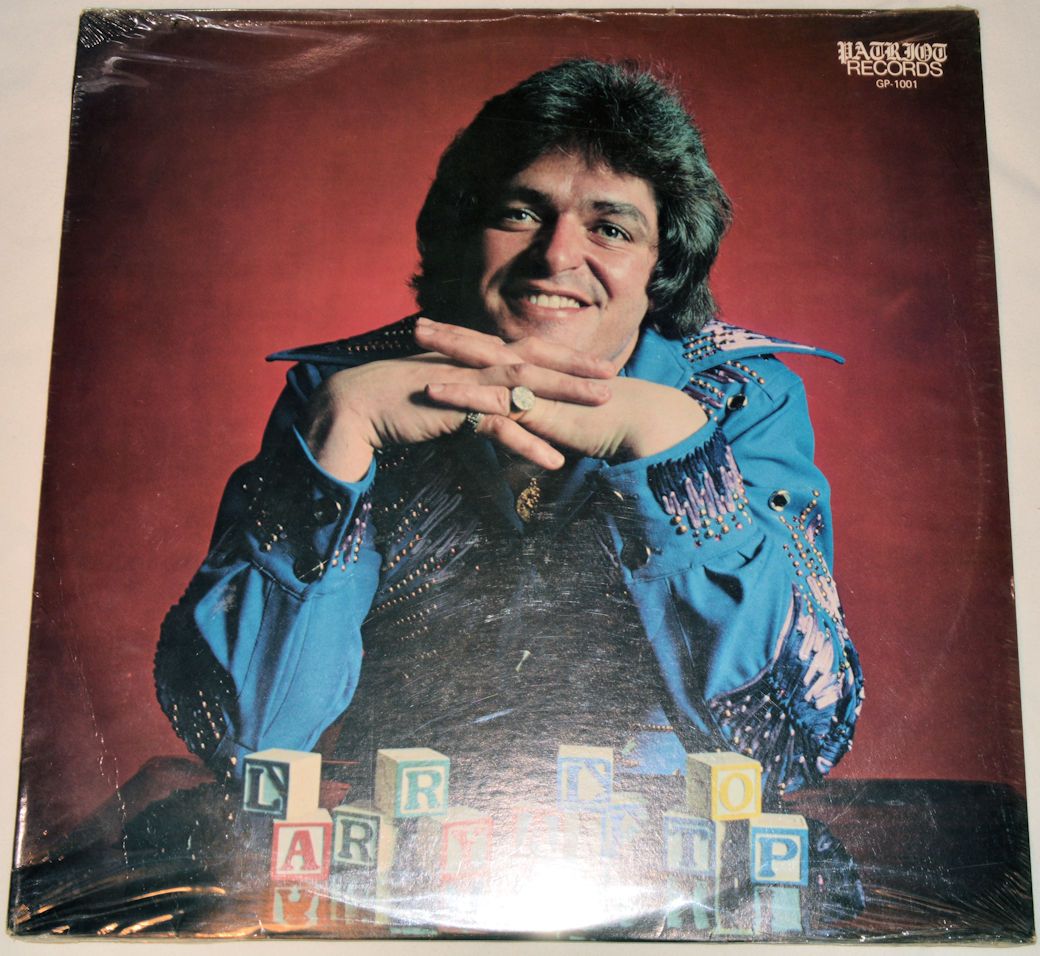 A vinyl record cover featuring a portrait of a man in a blue shirt and tie, with a background suggestive of a stage or performance setting, accompanied by colorful toy blocks.
