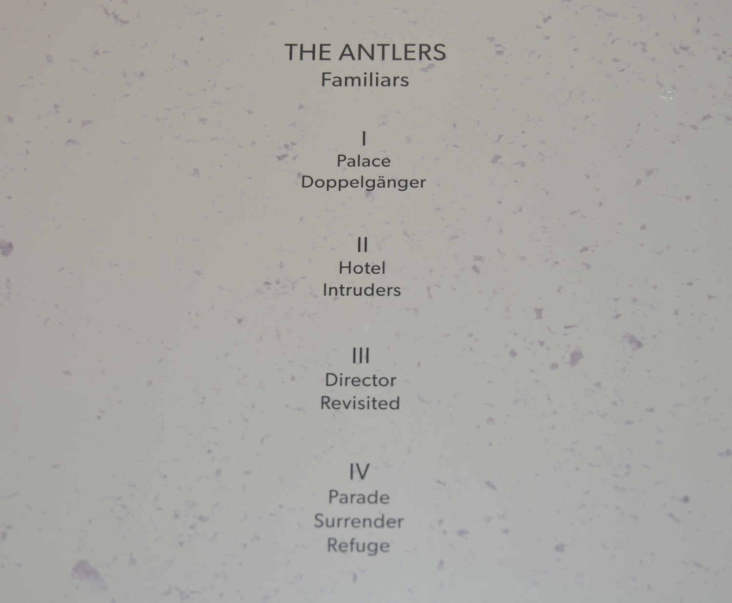 A purple vinyl record of Antlers - Familiars with a sculptural representation of two human figures in a similar purple hue.
