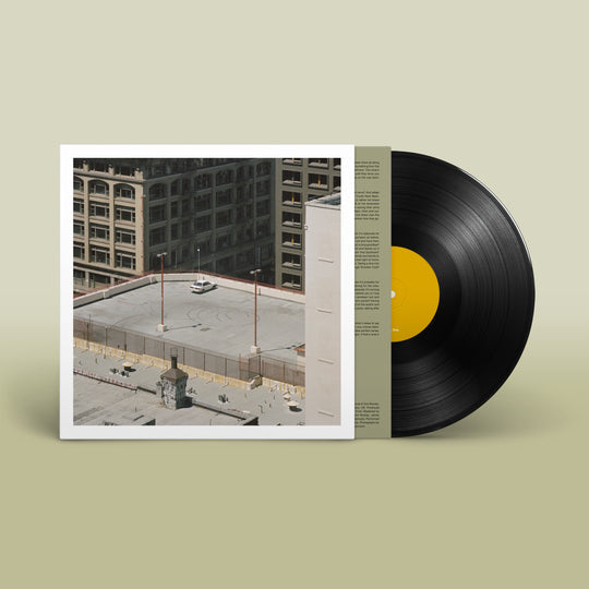 A vinyl record of Arctic Monkeys - The Car with a cityscape image on the cover.