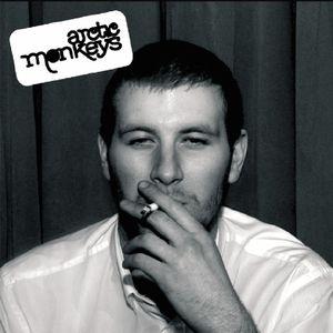 The image shows the cover of the Arctic Monkeys album 'Whatever People Say I Am, That's What I Am Not'. It features a black and white photo of a member of the band with a cigarette in his mouth.