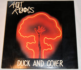 Used vinyl record label for Art Kritics' 'Duck & Cover'. The label features a red background with a silhouette of a duck and a hand, along with the title of the song and the artist's name.