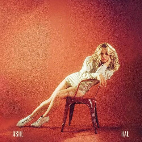 The image features a vinyl record cover with a woman seated on a chair, leaning forward with her hands resting on her knees. She is wearing a white top and white shoes, with her hair styled in a casual, flowing manner.