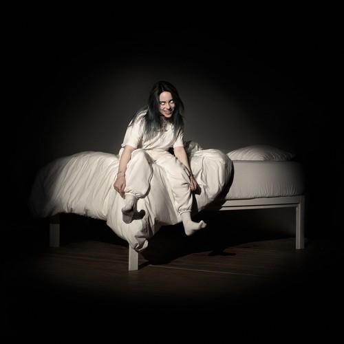 Billie Eilish 'When We All Fall Asleep' album cover with a person sitting on a bed in a dimly lit room, wearing a white outfit.
