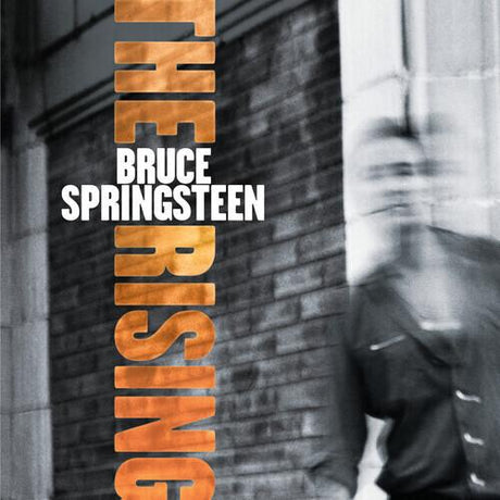 Album cover for 'The Rising' by Bruce Springsteen with a brick wall and blurred figure in the background.