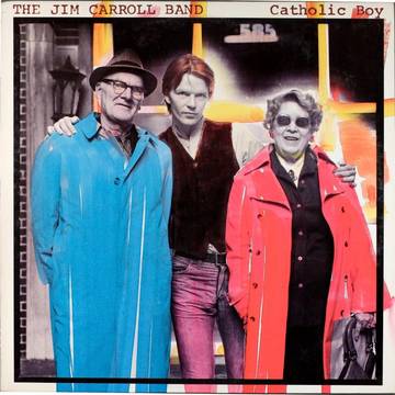 The image features the cover of "Catholic Boy (Deluxe Edition)," a vinyl record by Jim Carroll. The cover artwork displays a vibrant and colorful photograph of three individuals: a man in a hat and sunglasses, a woman in a red coat, and a second, unidentifiable person.