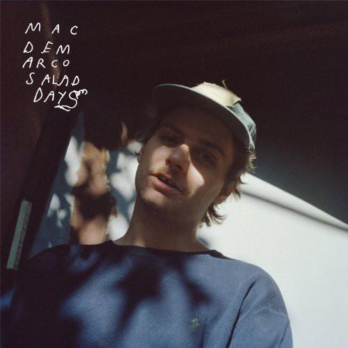 Mac DeMarco wearing a cap, sitting in a vehicle with a blurred background, with the album title 'Salad Days' written above.