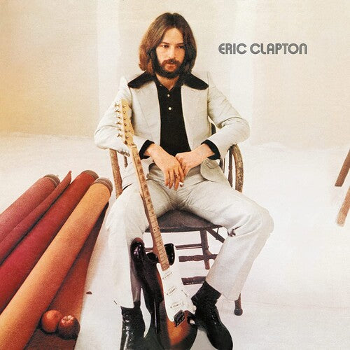 Album cover with Eric Clapton seated, holding a guitar, with a plain background.