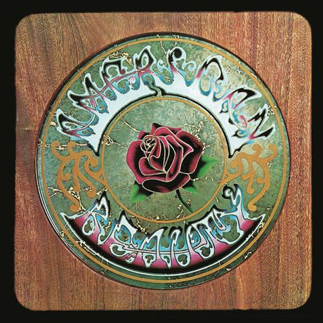 The image displays the album cover of 'American Beauty' by the Grateful Dead. It features a intricate, colorful artistic design with a prominent rose in the center, surrounded by stylized text that reads "American Beauty.