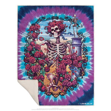 A multicolored fleece throw blanket with a Grateful Dead themed design, featuring a skeleton, roses, and a ocean background.