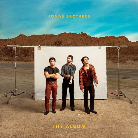 Album cover with three people standing in front of a white backdrop with 'Jonas Brothers' text.