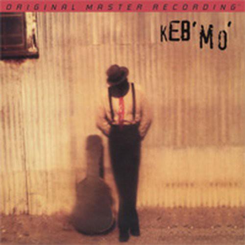 Album cover with a person in suspenders and hat, sitting next to an acoustic guitar, against a textured wall.