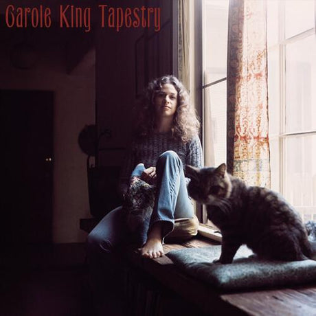 The image displays the album cover of Carole King's Tapestry, featuring a youthful Carole King seated on the floor with her pets in a cozy, indoor setting. The cover, stylized with warm tones and soft lighting, emphasizes the intimate and personal feel of the album.