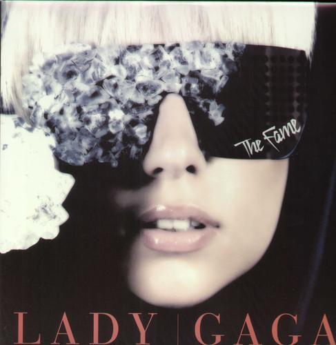 Album cover of Lady Gaga's 'Fame' featuring Gaga with a black and white floral mask on her face, predominantly in black and white with a close-up of her face.