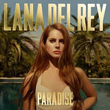 An album cover featuring Lana Del Rey with red hair, wearing a white bikini, standing near a pool. The text 'LANA DEL REY' is in large gold letters above her, and 'PARADISE' is in smaller gold letters at the bottom.