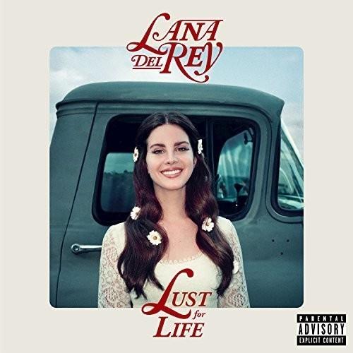 This image features the album cover of "Lust for Life" by Lana Del Rey. The cover art displays Lana Del Rey with a broad smile, seated in a vintage car, dressed in a white outfit adorned with floral patterns.