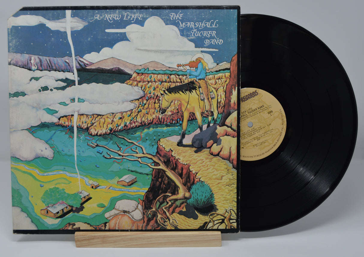 Vinyl record of The Marshall Tucker Band, A New Life, with a colorful cover featuring a horse and a landscape illustration.