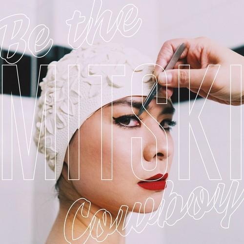 Woman applying makeup with text overlay 'Be the MITSUKI Cowboy' on a light background