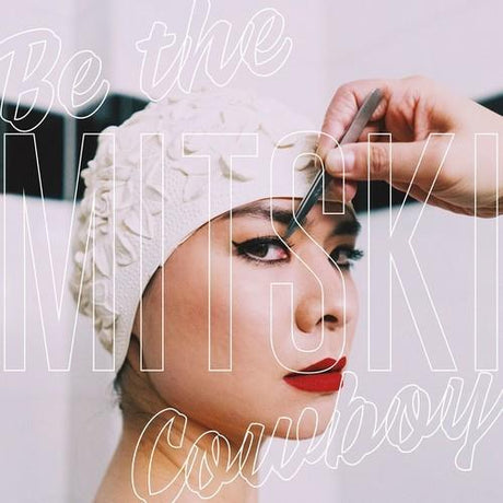 Woman applying makeup with text overlay 'Be the MITSUKI Cowboy' on a light background