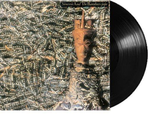 This image features the vinyl record of Siouxsie & Banshees' fourth studio album, titled "JuJu." The album cover displays an intricate and visually textured design, with a monochrome photograph of a cityscape overlaying on a patterned background, possibly representing an abstract or artistic rendition.