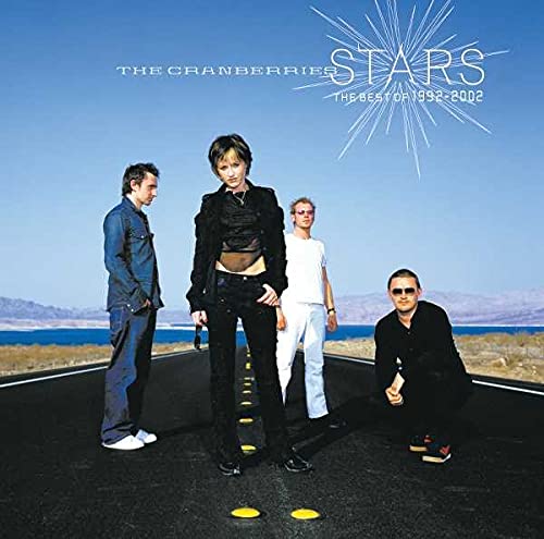 The Cranberries band members posing on a road with a scenic background, used as album art for 'Stars (The Best Of 1992-2002)'.