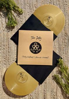 Two gold vinyl records with a black cover featuring a logo and text on a wooden surface.